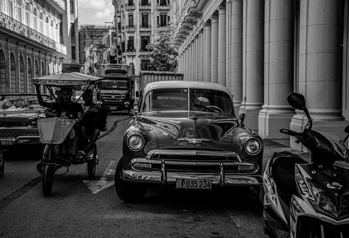 Black and white photo of classic cars on a bustling street in Havana, Cuba.