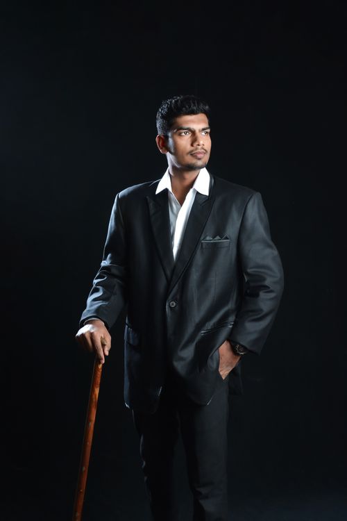 Free Stylish portrait of a man in formal attire, striking a pose against a black background. Stock Photo