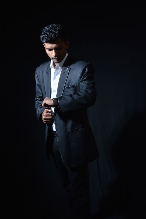 Free Elegant man in a suit adjusting his cufflinks in a studio setting, showcasing modern fashion. Stock Photo