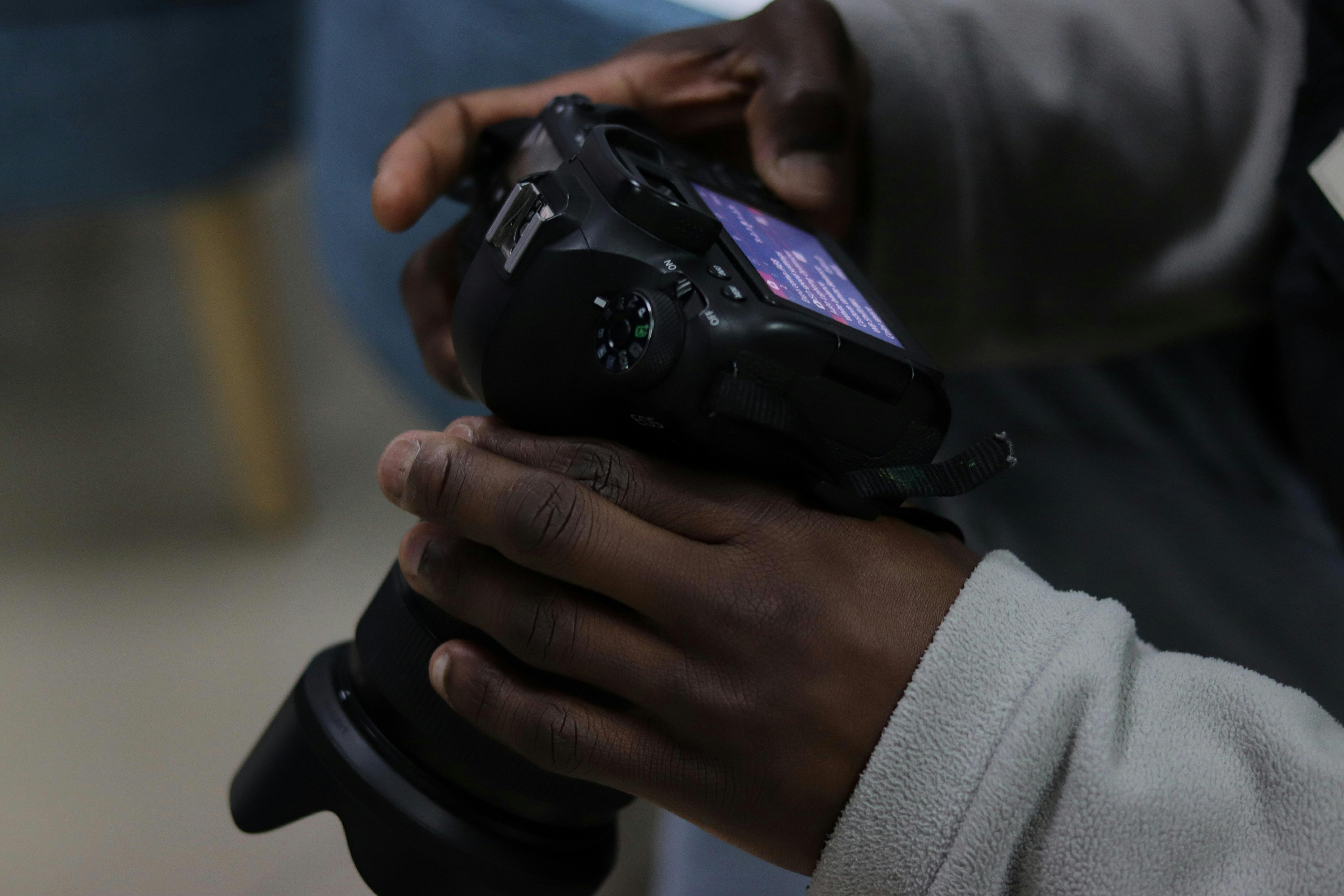 Close-up of an adult handling a DSLR camera indoors, focusing on photography details.