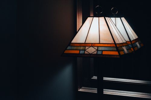 Free Art deco style lamp reflects in a mirror, creating a warm and atmospheric feel. Stock Photo