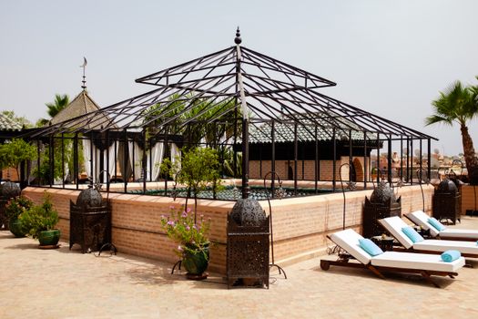 Beautiful Marrakesh resort with poolside loungers and exquisite architecture under a clear sky.
