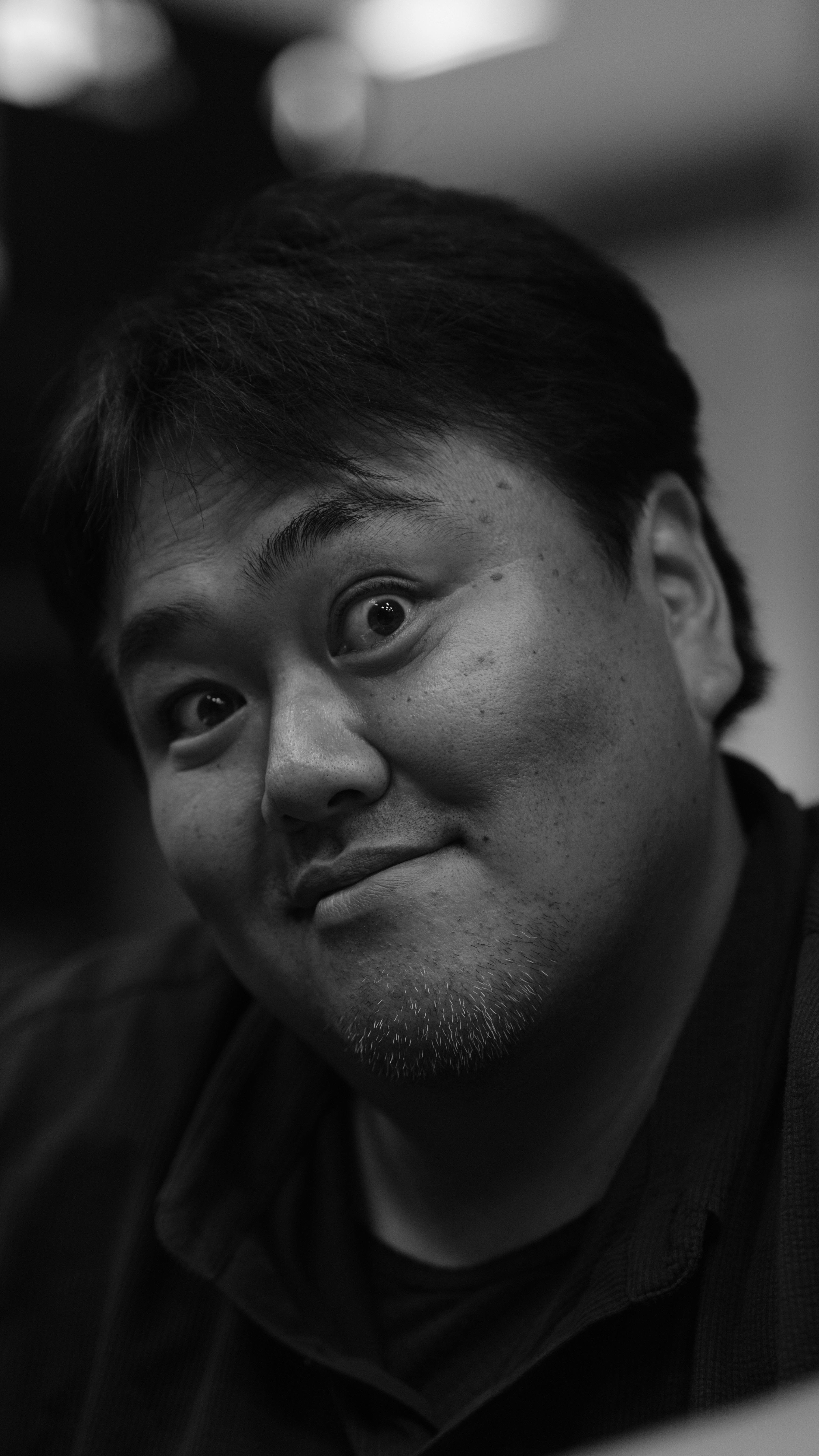 A close-up black and white portrait of a smiling man with a playful expression.