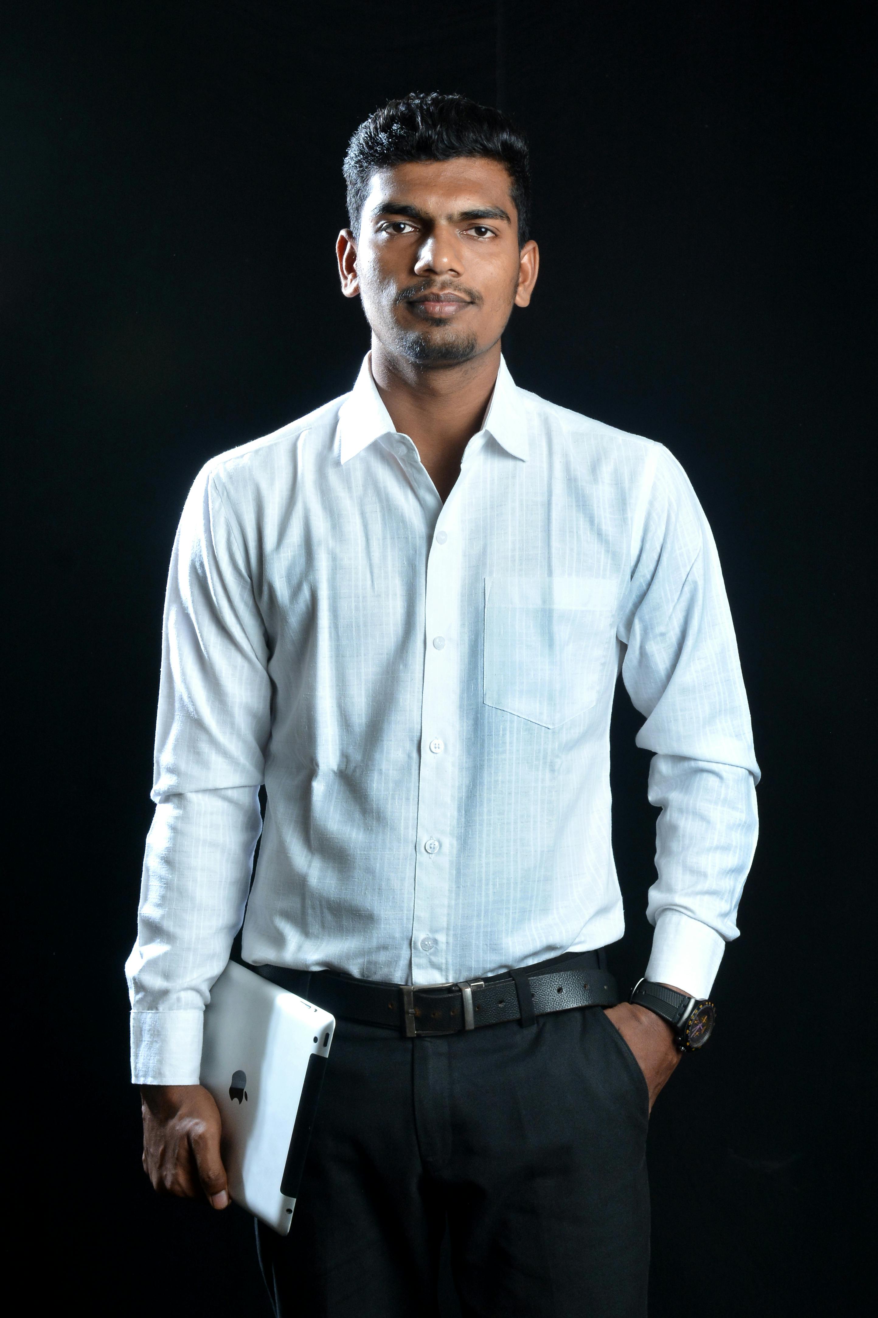 Confident businessman in formal attire holding a tablet against a dark background.