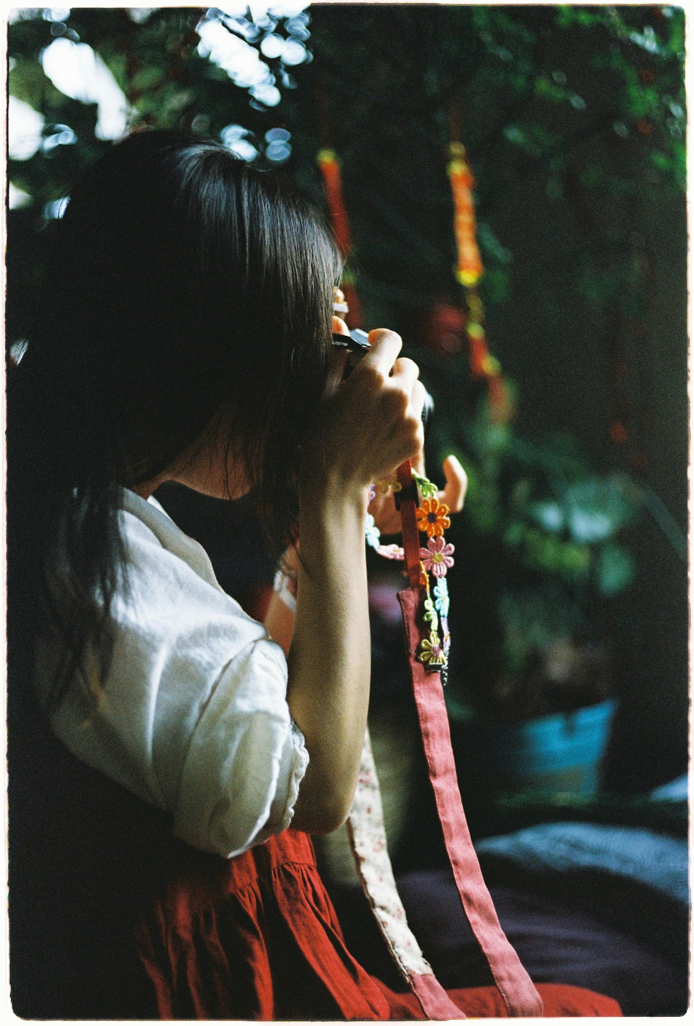 Woman holding vintage camera surrounded by nature, creating a nostalgic mood.