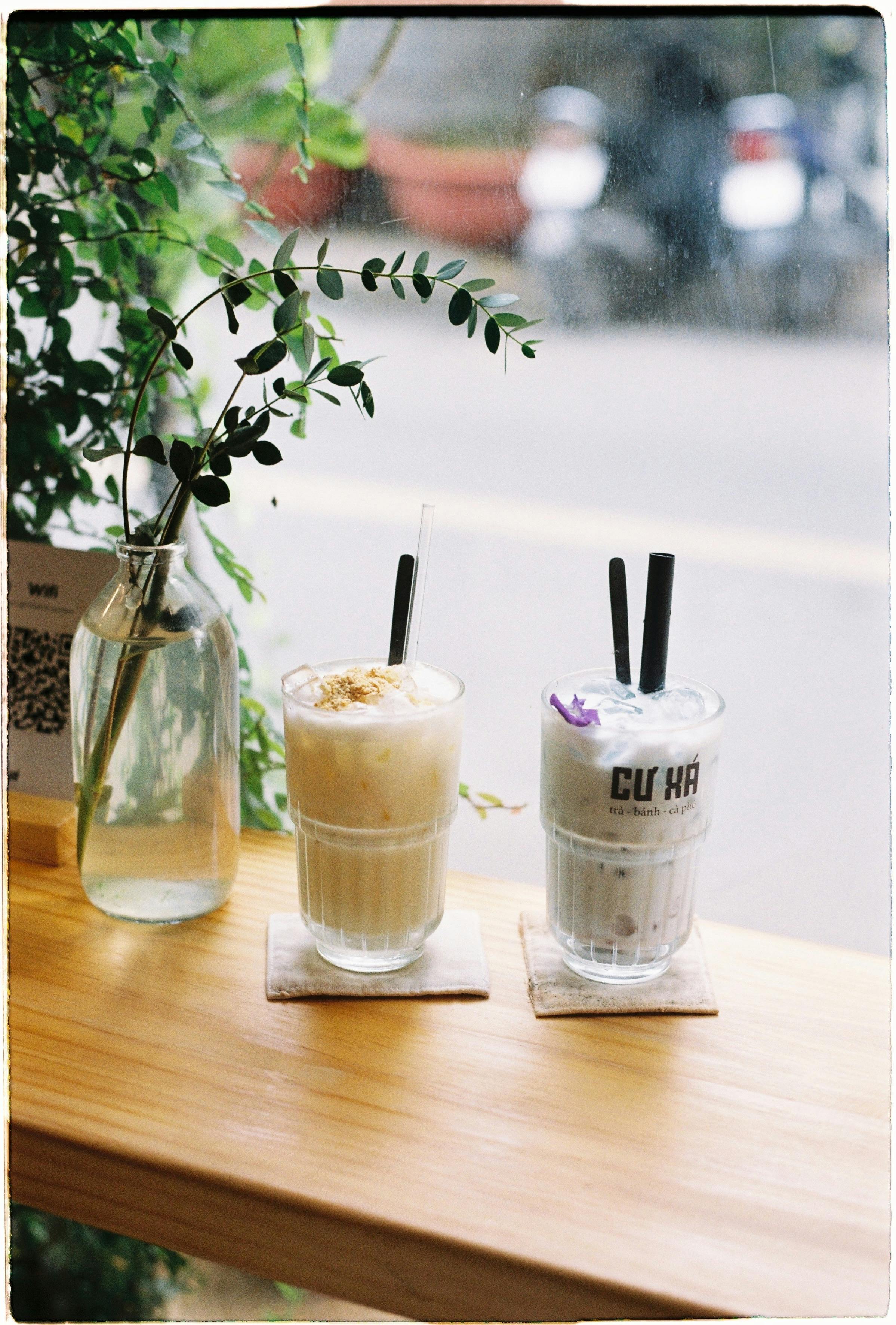 Two iced drinks on a wooden table by a window, creating a relaxing café atmosphere.