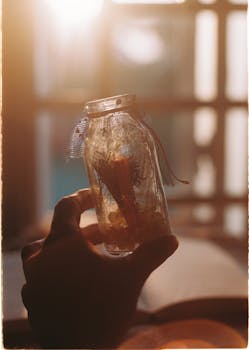 A handcrafted decorative jar is held against a warm sunset light, creating a serene ambiance.