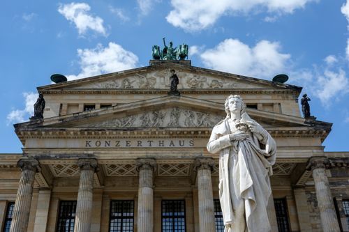 Free Front view of the Konzerthaus Berlin featuring its iconic statue under a bright blue sky. Stock Photo