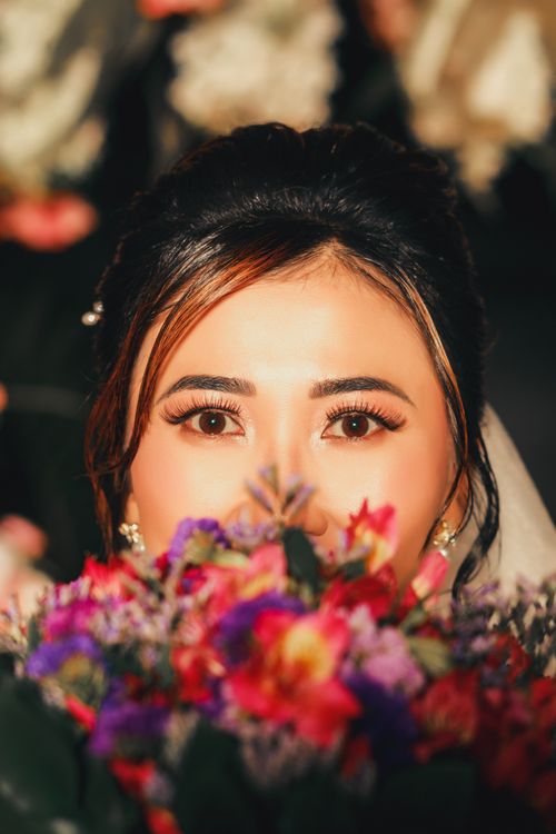 Free A beautiful bride holding a colorful bouquet, captured in a candid moment. Stock Photo