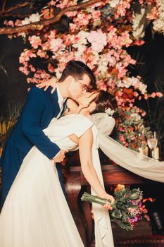 Bride and groom share a kiss under cherry blossoms, capturing intimate wedding moments.
