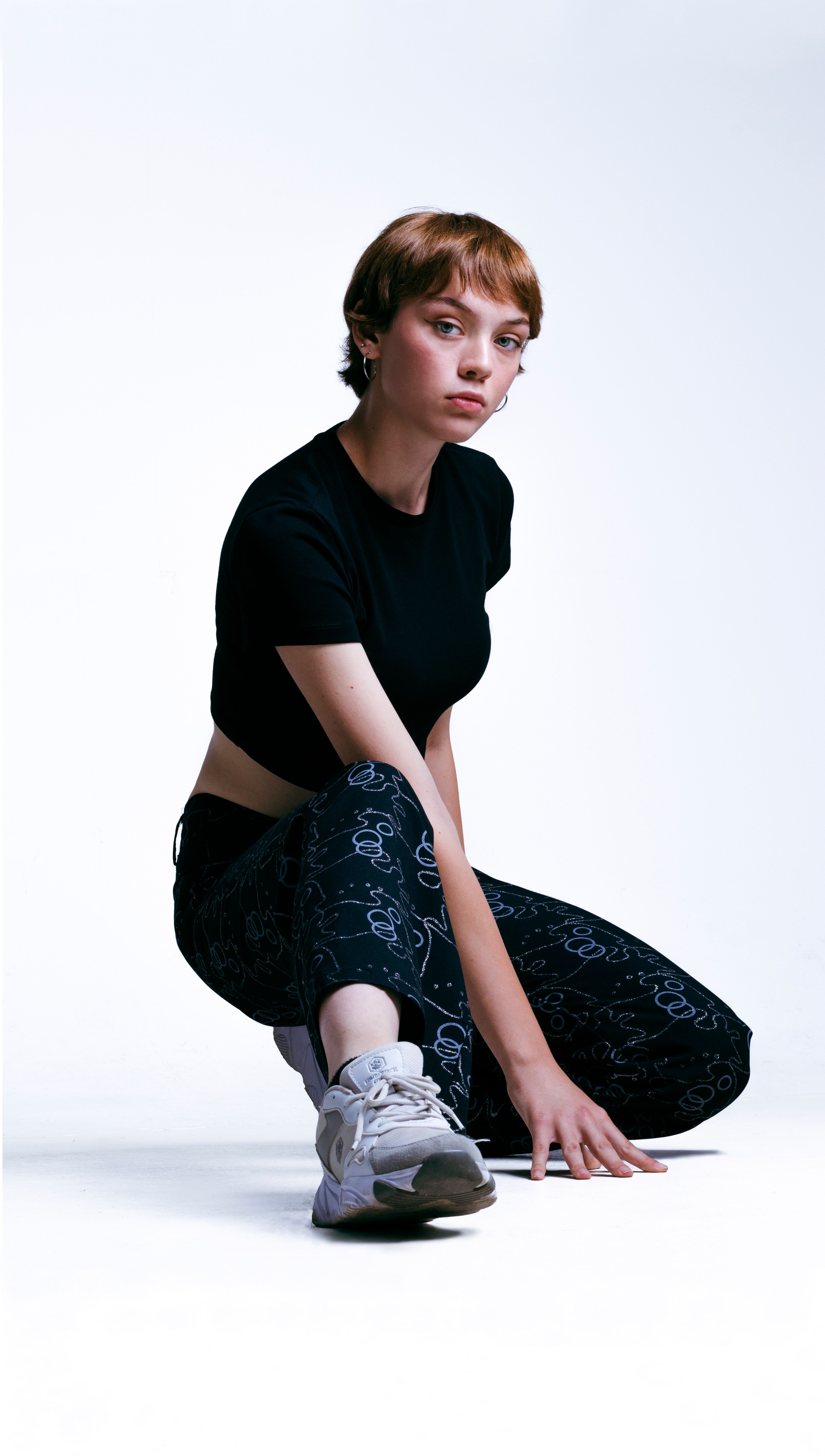 Stylish woman in modern sportswear posing confidently in a studio setting.