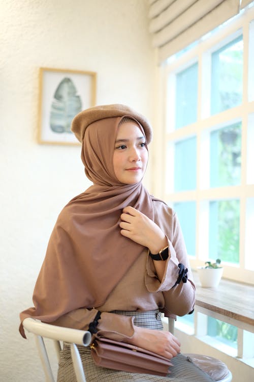 Woman Holding Hear Headscarf While Sitting