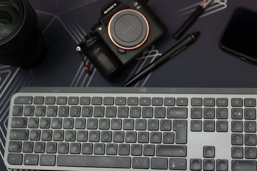 A digital workspace featuring a camera, keyboard, smartphone and accessories on a desk.