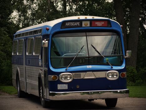 Classic blue bus at Gibraltar Point in Toronto, surrounded by trees.
