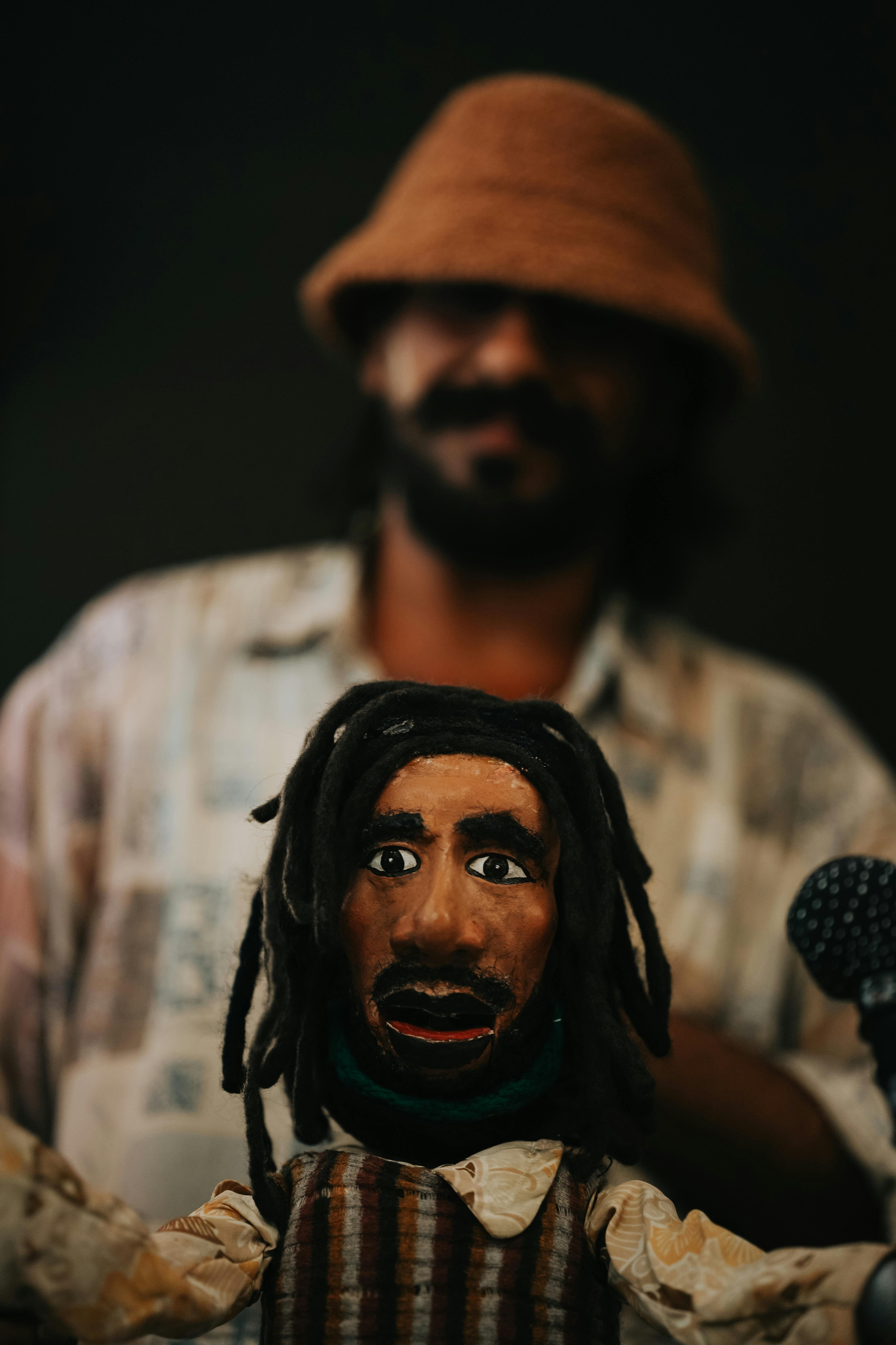 Handcrafted puppet with dreadlocks in focus, artisan in background, Ankara setting.