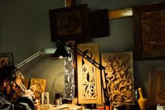 Intricate wood carving by a skilled artisan in a detailed workshop scene.