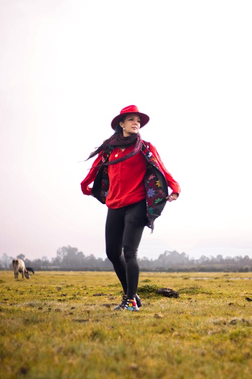 Woman in a Red Hat Standing on a Field