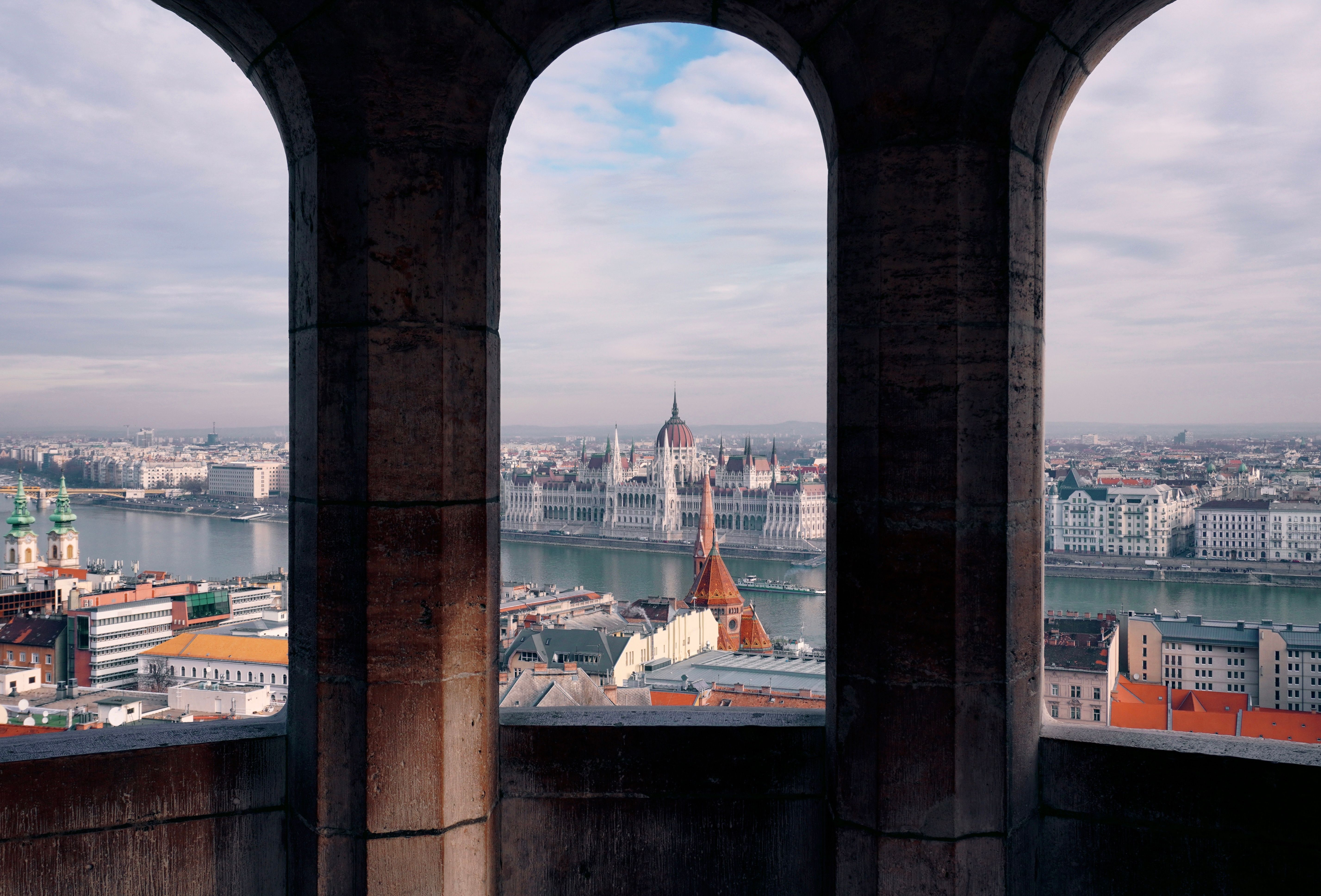 Scenic view of the Hungarian Parliament Building through Fisherman's Bastion arches in Budapest.