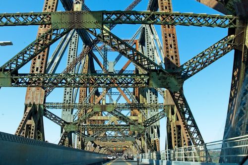 Free Close-up of a historic steel truss bridge with intricate ironwork against a clear blue sky. Stock Photo