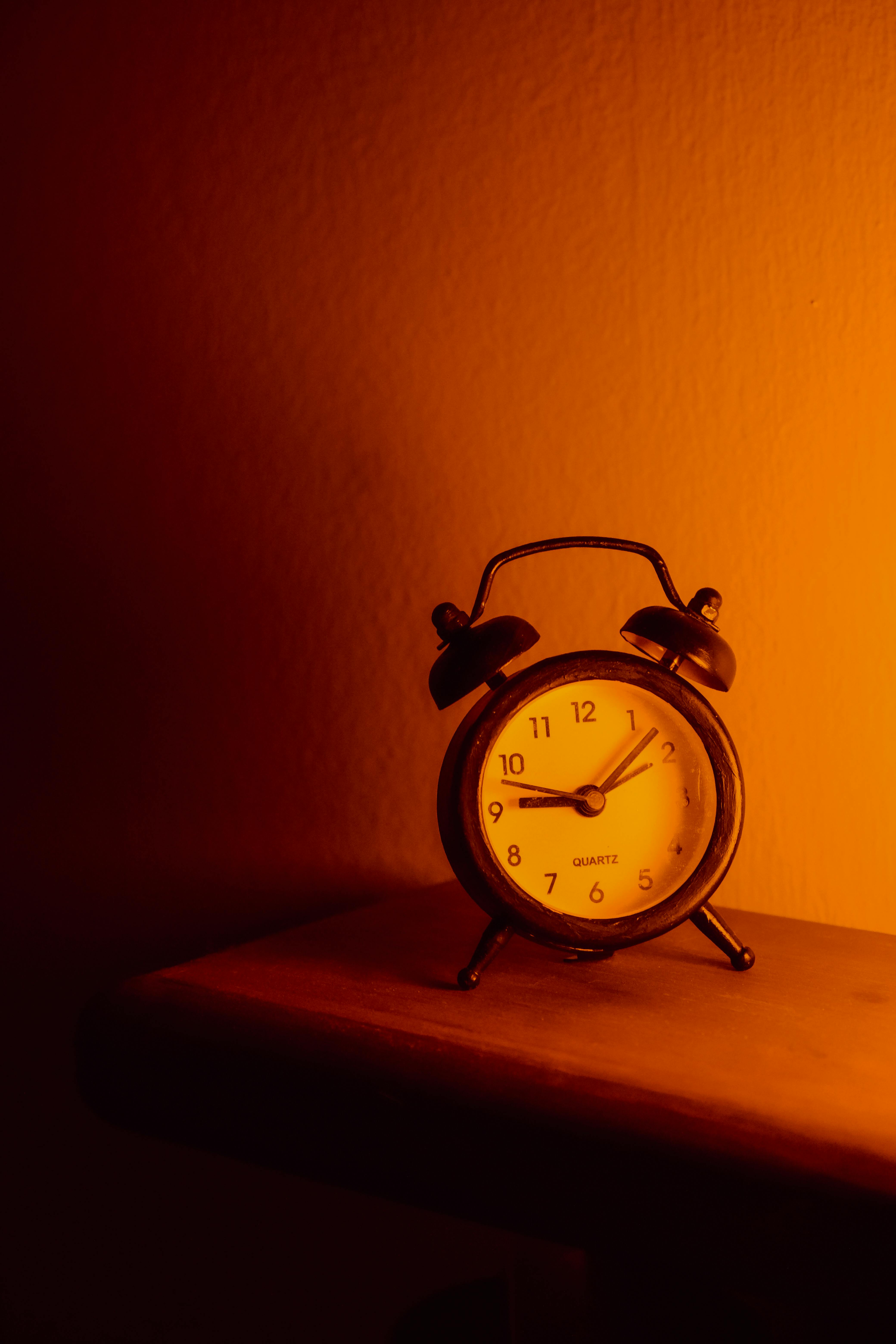 White alarm clock on brown wood desk and cream wallpaper textured  background with copy space Stock Photo | Adobe Stock