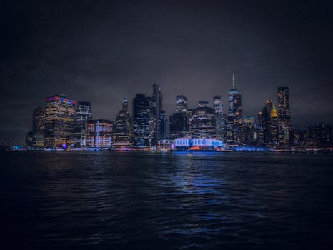 Stunning nighttime view of the illuminated New York City skyline reflecting on water.