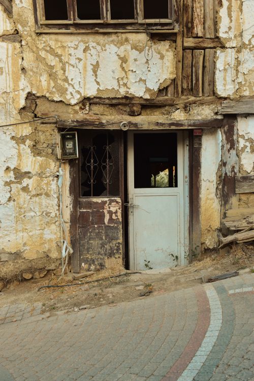 Free Weathered facade of an abandoned house, showing a rustic entrance with peeling paint. Stock Photo