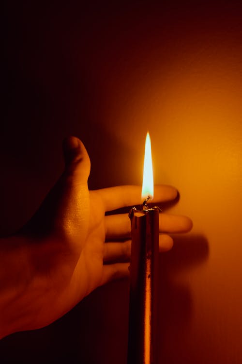 Close-up of Hand near Lighting Candle