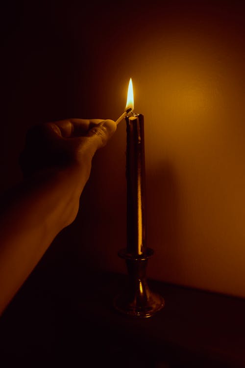 Close-up of Person Hand Lighting Candle in Dark