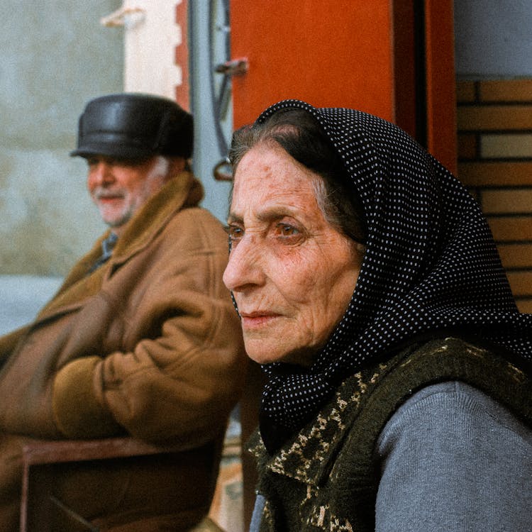 Elderly Man And Woman Sitting Outside 