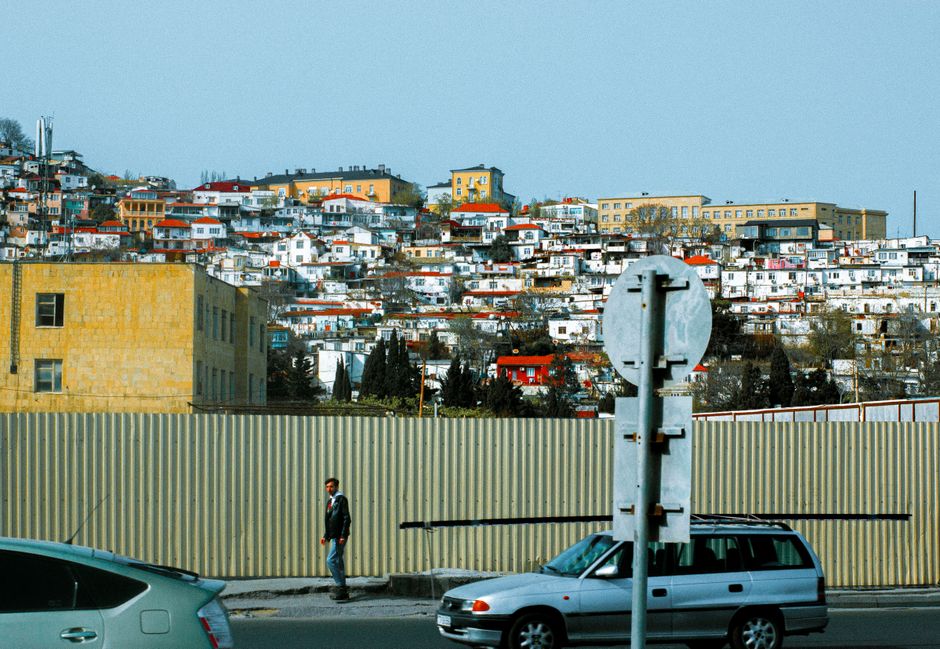 Colorful hillside homes under a clear blue sky in an urban setting with street view.
