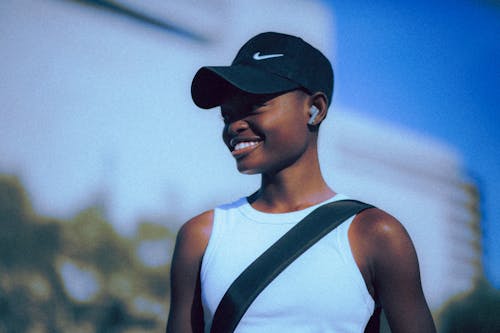 Smiling Girl in Baseball Hat with Wireless Headphones