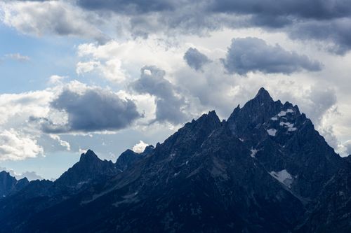 Free Majestic mountain peaks set against a dramatic, cloudy sky on a summer day. Stock Photo