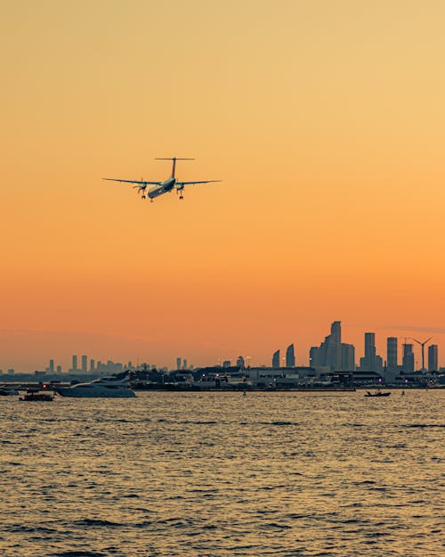 Airplane Flying against Boston Cityscape at Sunset