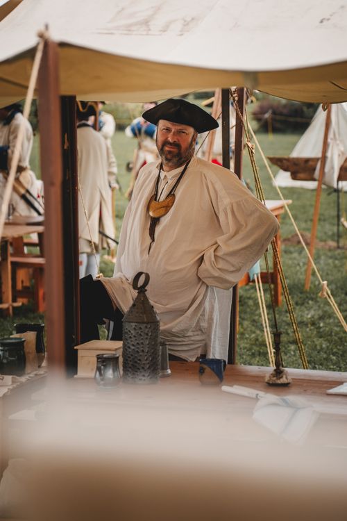 Free A man dressed in a 19th-century French military costume poses in a reenactment camp site. Stock Photo