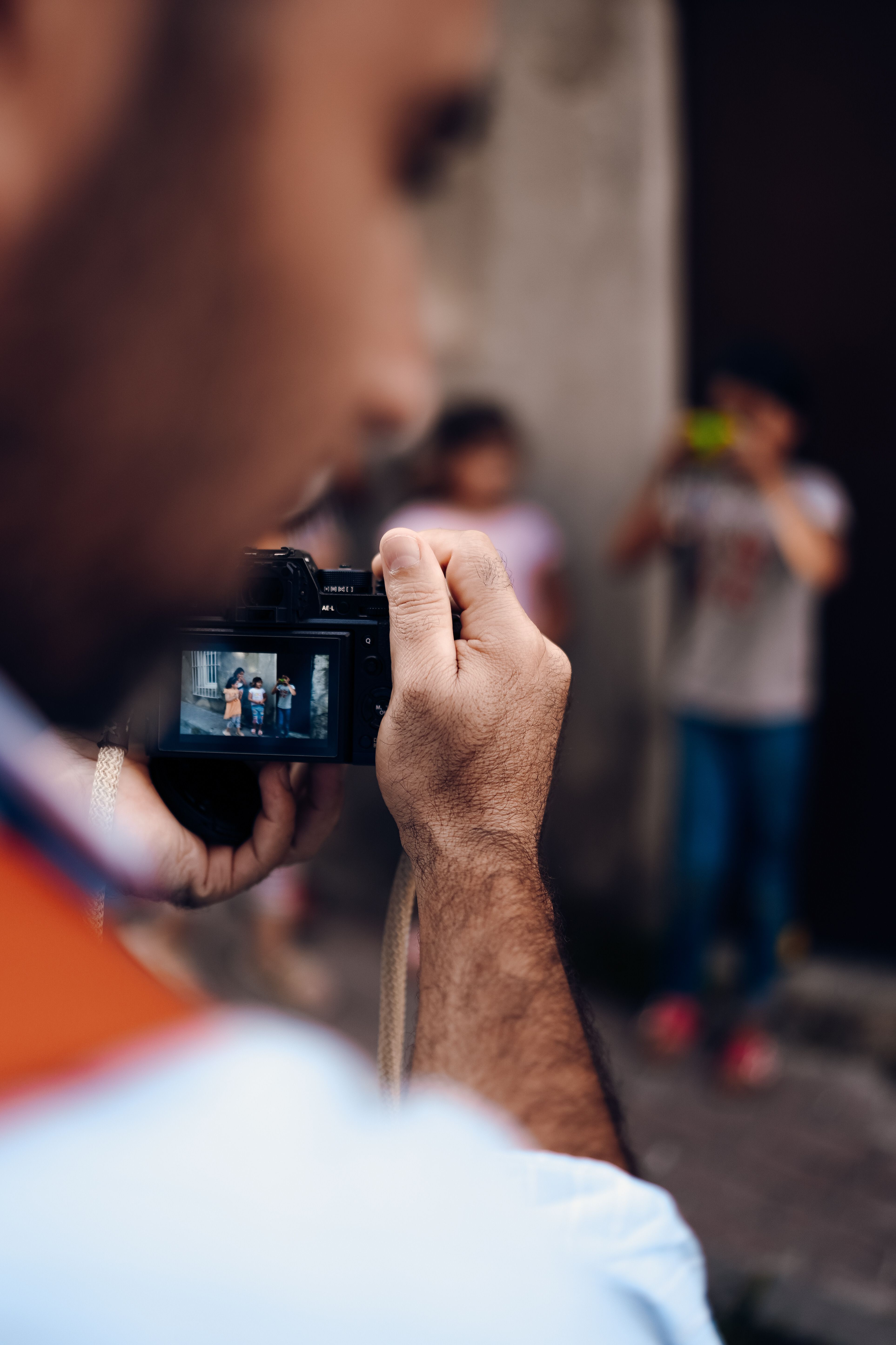 Photographer focuses on subjects while capturing a vibrant city street scene.