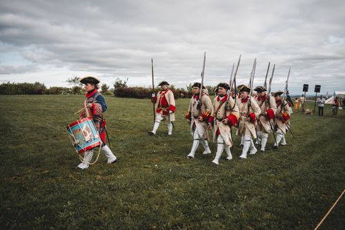 Free A group of men in historical military uniforms performing a reenactment march outdoors. Stock Photo