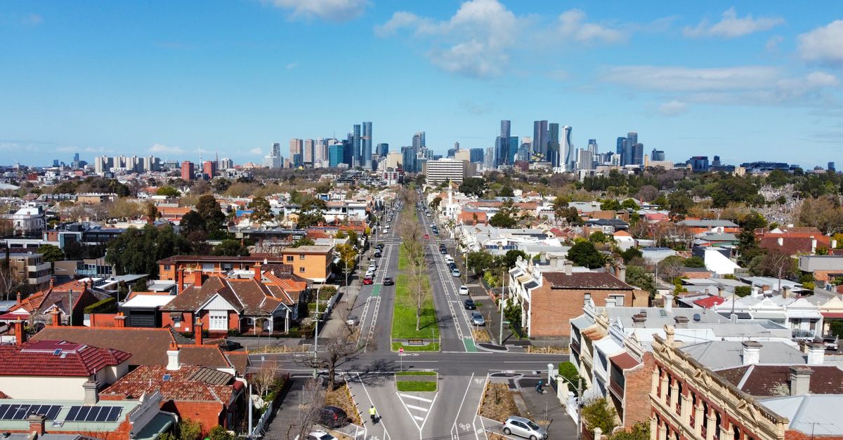 Aerial view of Carlton North neighborhood with Melbourne's skyline under a clear day sky.