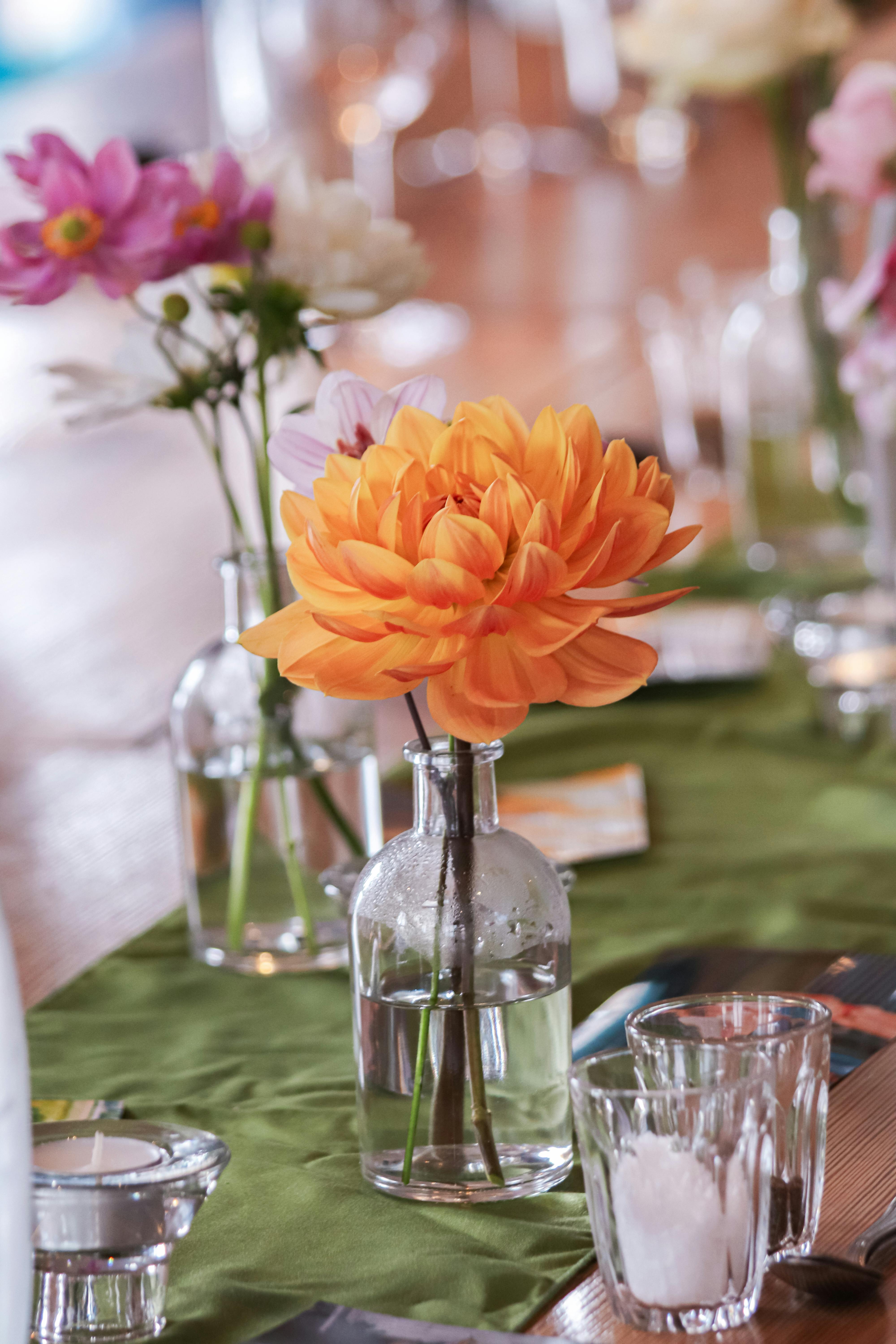 Bright orange and pink flowers in glass vases add a touch of elegance to the table decor.