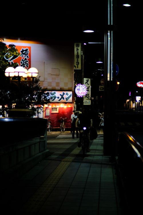 Free Explore the vibrant lights of an urban street at night, showcasing neon signs and bustling city life. Stock Photo