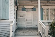 A charming wooden house facade with blue shutters and front porch, exuding vintage warmth.