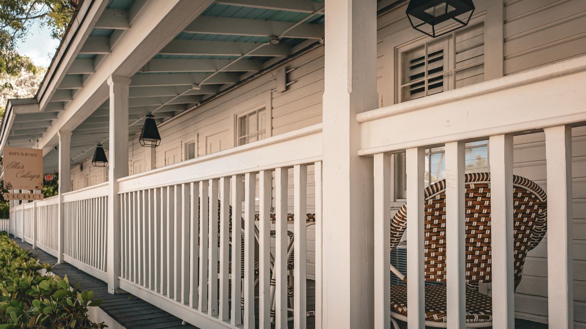 A porch with white balusters. A spacer block cut to the gap width keeps every opening the same.