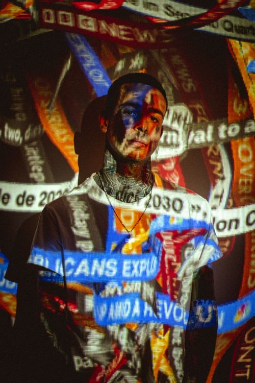 Free A person stands amidst a colorful projection of news headlines, creating an abstract visual effect. Stock Photo