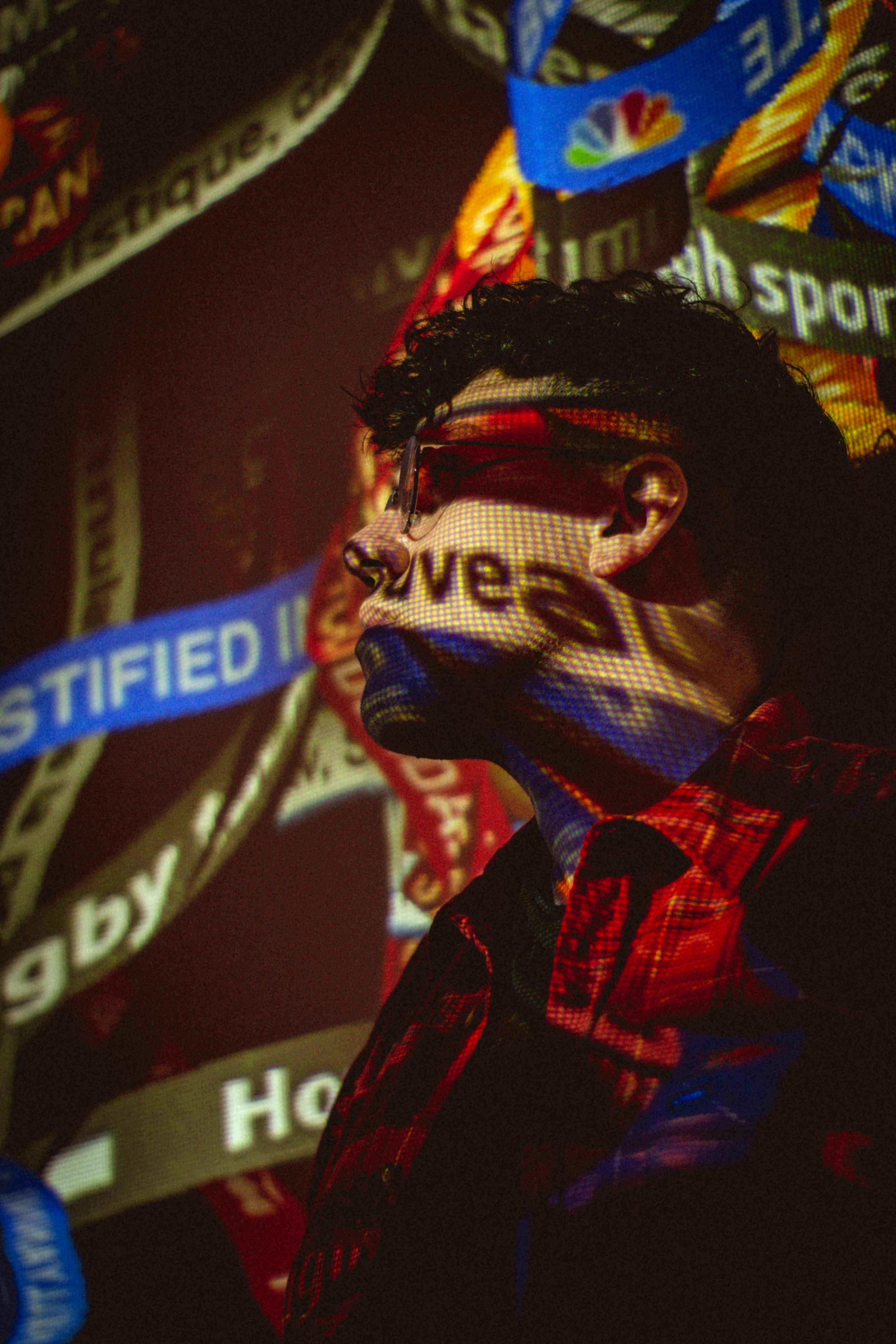 Young man in glasses with news headlines projected on him, creating a dramatic and moody atmosphere.