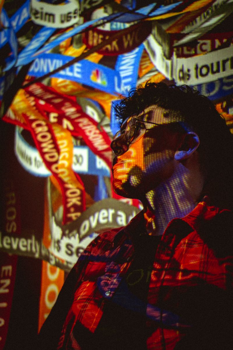 Digital artwork projected across a young man's face in a dark room