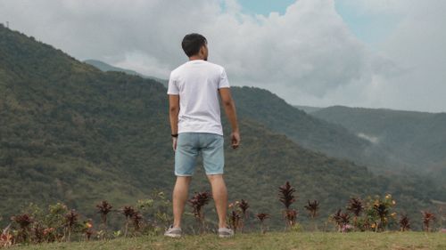 Free Man in casual attire standing on hill, observing lush Bacolod mountains. Stock Photo