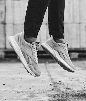 Monochrome image featuring a person in midair wearing trendy Reebok sneakers.