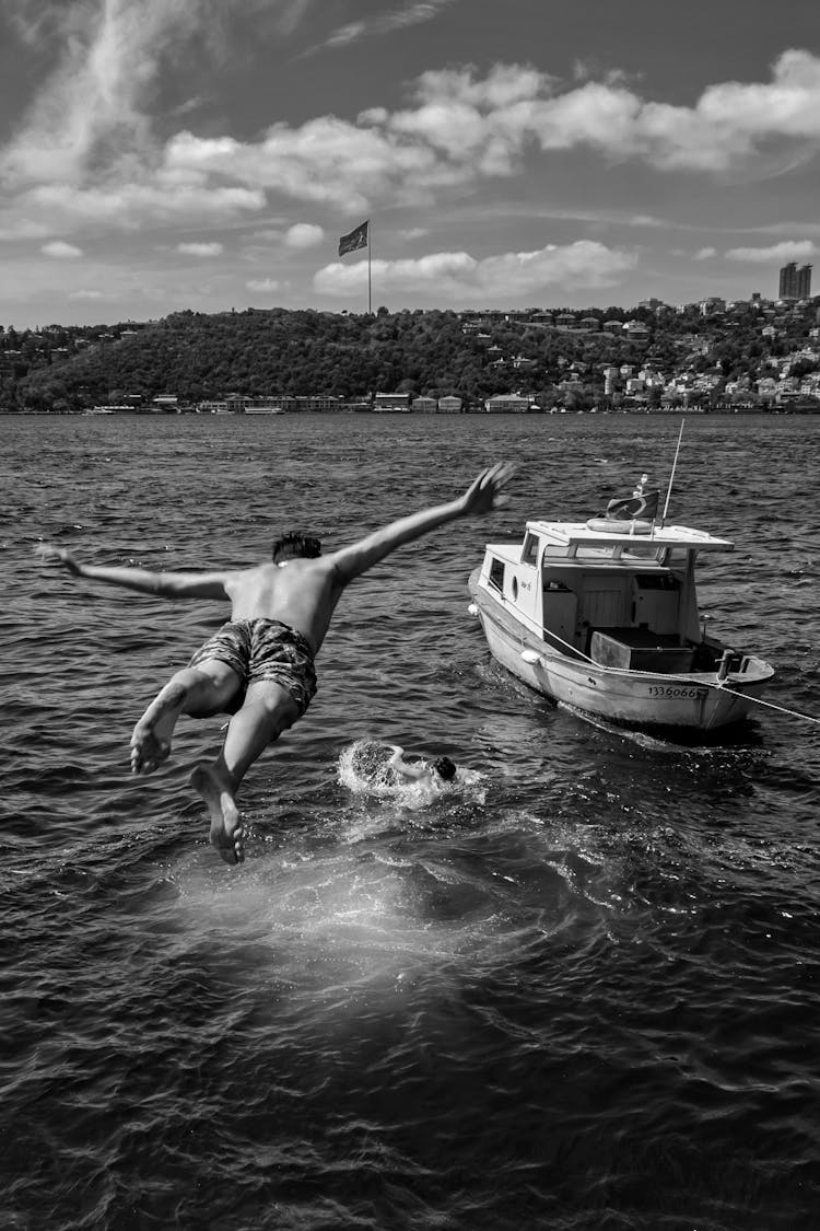 A Man Jumping Into The Water From A Boat 