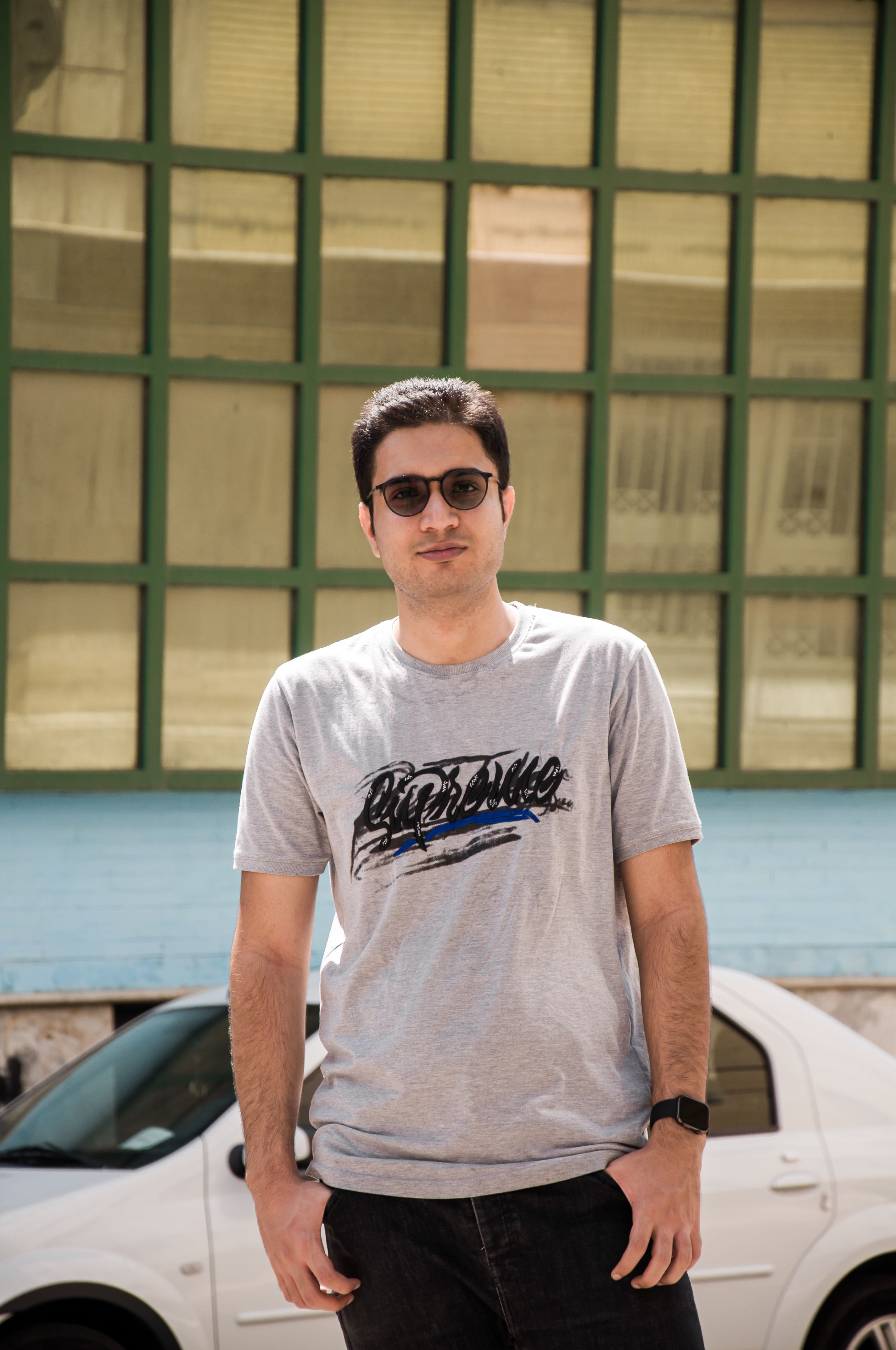Young man in casual outfit wearing sunglasses on a sunny day outdoors.