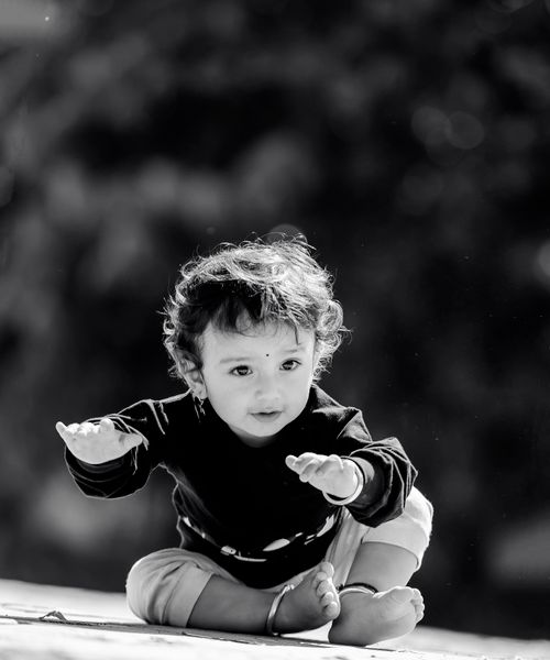 Free Adorable toddler enjoying playtime outdoors in a park, captured in a black and white photo. Stock Photo