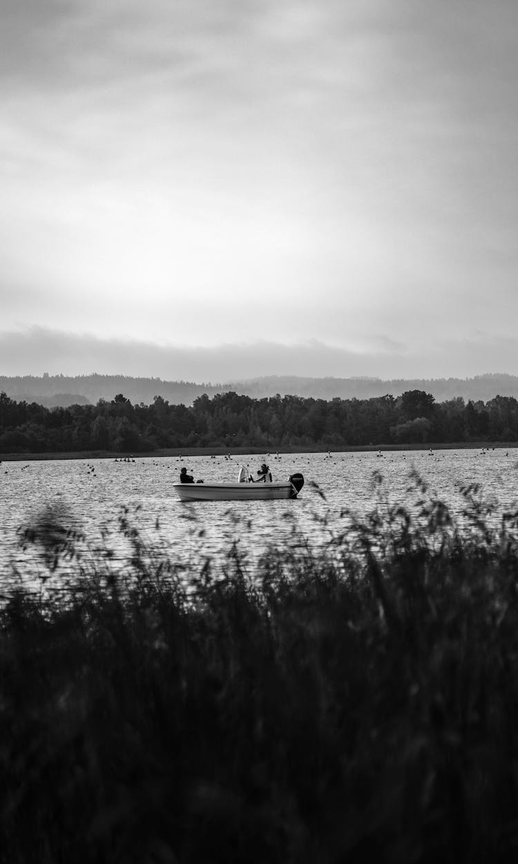 Black And White Photo Of A Boat On A Lake 